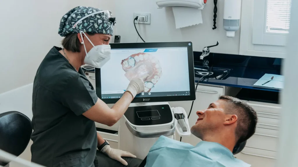 Odontoiatra mostra a un paziente il modello 3D della sua arcata dentale sul monitor dello scanner intraorale.